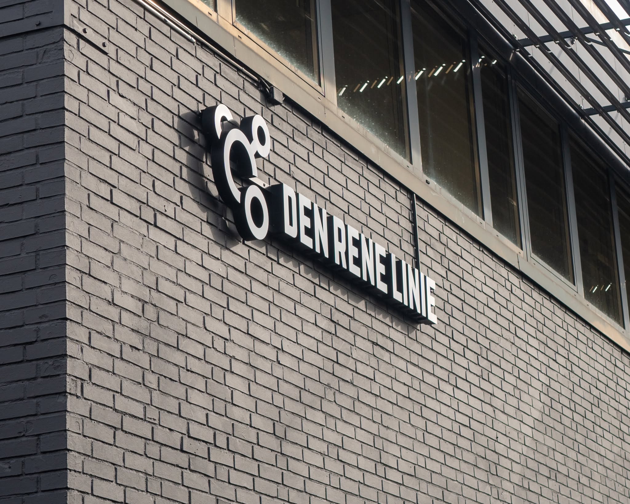 Den Rene Linies logo og navn på den mørke murstensfacade ved kontoret i Black Box Business Building